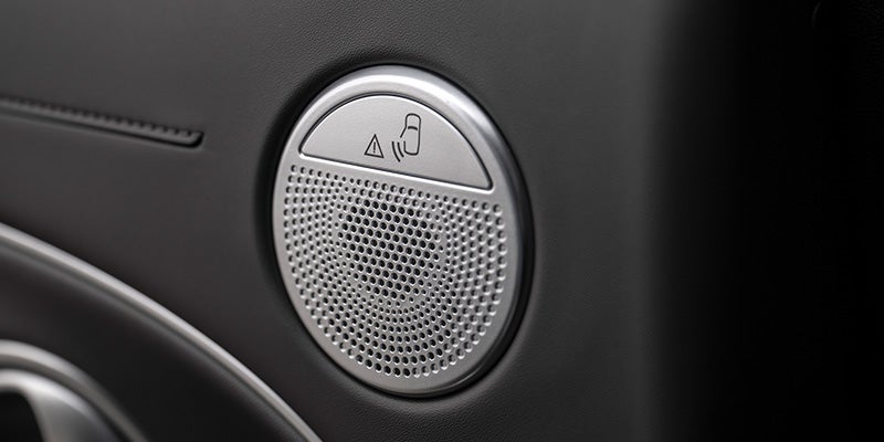 Vista de cerca del volante beige, el velocímetro digital y la pantalla del sistema de infoentretenimiento de un automóvil.