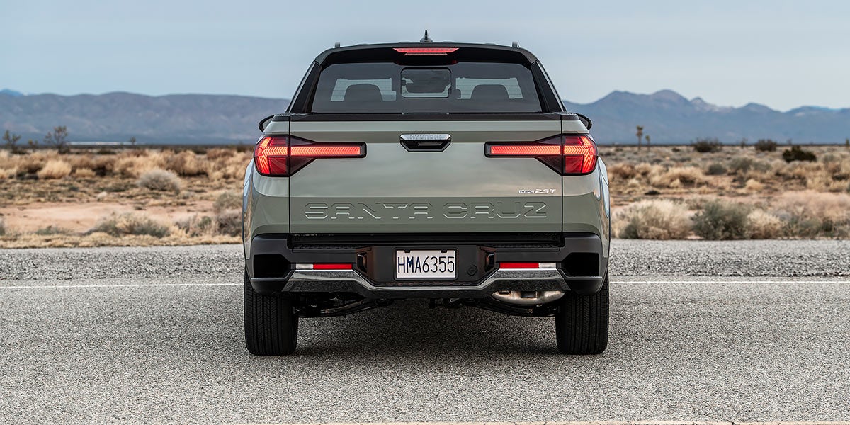Una camioneta Hyundai Santa Cruz de color verde pálido circula por una carretera sinuosa con vegetación montañosa.