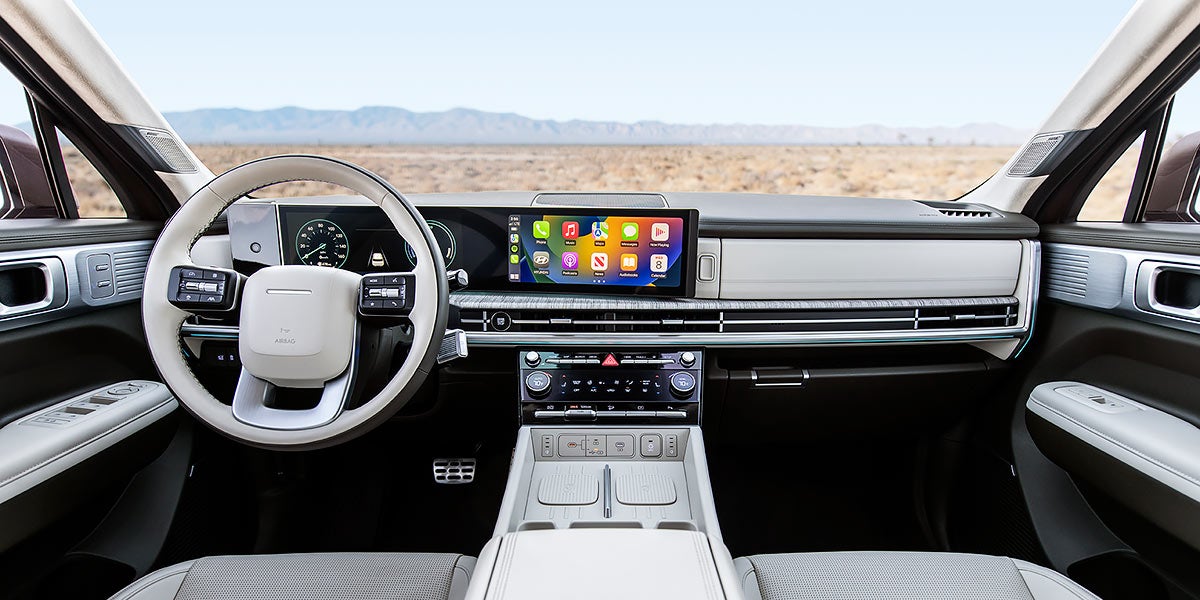 Vista interior de un coche con volante blanco y gris, panel de instrumentos digital y pantalla de navegación.