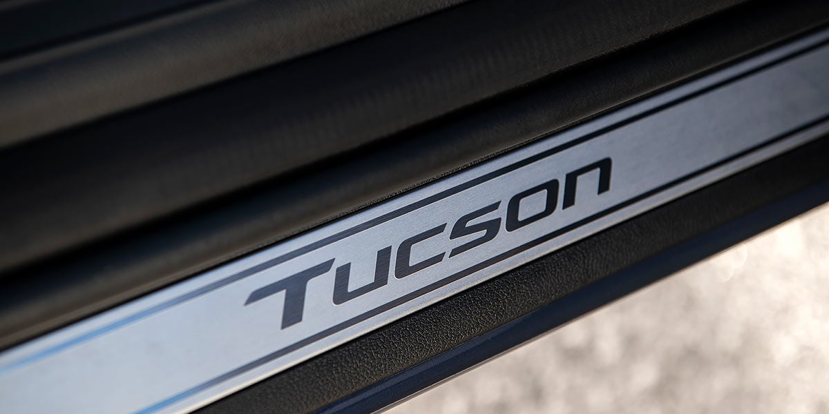 Un Hyundai Tucson azul oscuro circulando por una sinuosa carretera de montaña con un fondo borroso que indica velocidad.