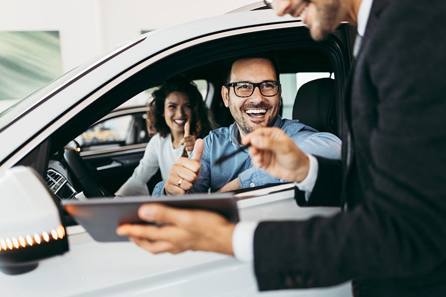 Couple talking with car salesman